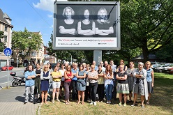 Schirmherr Oberbürgermister Thomas Eiskirch mit Vertreterinnen und Vertretern des Bündnisses sowie das Plakat der Kampagne „Die Würde von Frauen und Mädchen ist unantastbar. In Bochum und überall.“