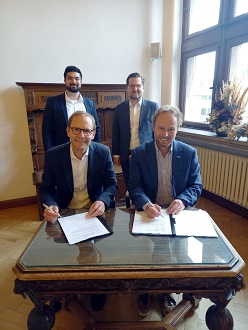 v. l. (vorne) Stefan Rüther, Chief Commercial Officer OXG, und Stadtdirektor und Digitalisierungsdezernent Martin Murrack bei der Unterzeichnung des Letter of Intent; (stehend) Thomas Preiß, Key Account Manager Kommunen und Timo Seidel, General Counsel OXG