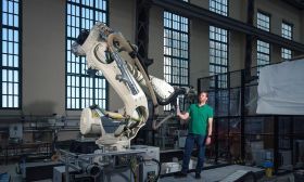 Timo Hartmann an einem Roboterarm. Mit dem Roboterarm wird erforscht, wie das Prinzip des Recyclings in der Bauwirtschaft verankert werden kann. Der Roboterarm steht in der Peter-Behrens-Halle der TU Berlin, einer weltweit einmaligen Versuchshalle.  Kevin Fuchs